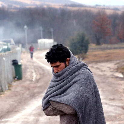 un migrante cerca di scaldarsi nel campo di Lipa